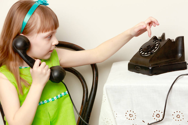 Dziewczyna rozmawia na czarny, stary telefon z płyty spinning.  - Zdjęcie, obraz