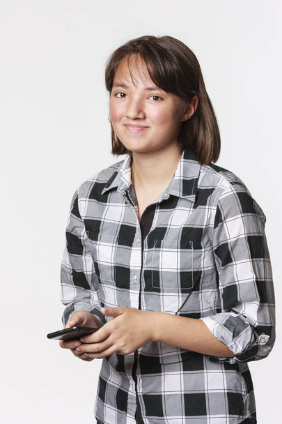 Konzeptionelles Foto eines Teenie-Mädchens beim SMS-Schreiben auf ihrem Handy in einem Studio-Setting. - Foto, Bild