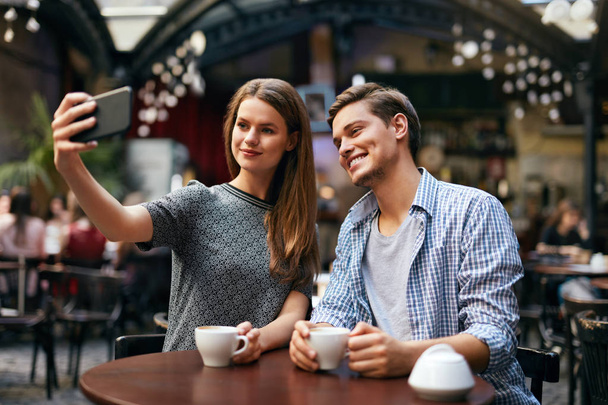Couple Making Photo On Mobile Phone In Cafe - Photo, Image