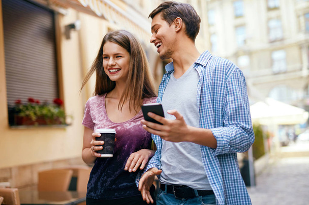 Couple Using Mobile Phone And Drinking Coffee Outdoors - Valokuva, kuva