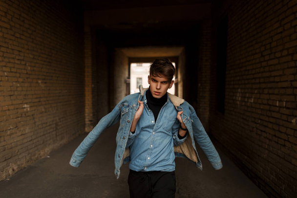 Модна молода чоловіча модель в стильному джинсовому одязі позує на вулиці
 - Фото, зображення