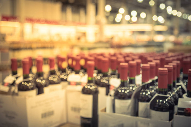 Blurred and close up view group of red wine bottles in cellar at wine section of modern distribution warehouse. Inventory, logistic, business, wholesale, export concept. Beverage alcohol background. - Photo, Image