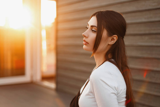 Beautiful fashionable woman in a white T-shirt at sunset - Photo, Image