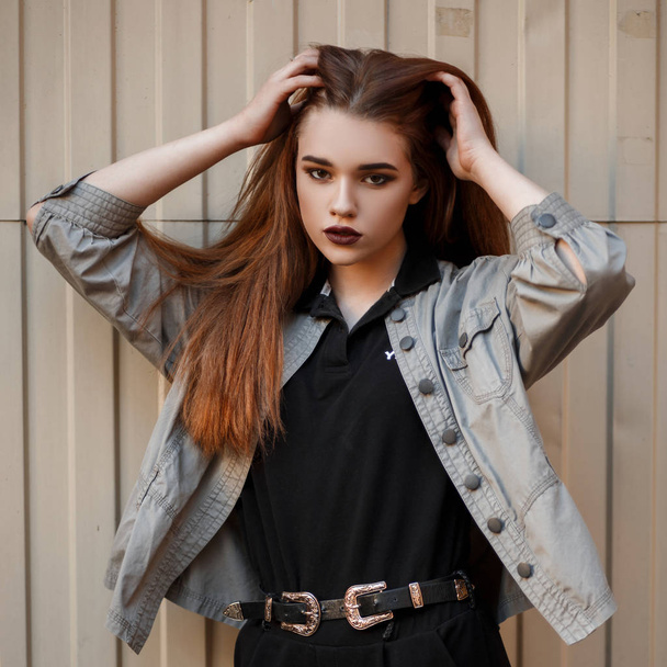 Kaunis nuori nainen malli musta muodikas poolo ja tyylikäs takki lähellä metalliseinää kadulla
 - Valokuva, kuva