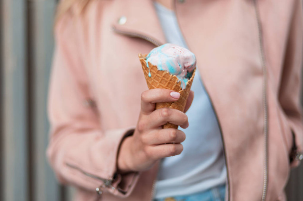 Delicious pink and blue ice cream. Girl holds a wafer cone with ice cream - Zdjęcie, obraz