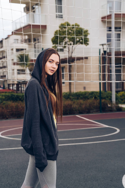 confident slender girl with long hair trains on the sports ground, leads an active lifestyle - 写真・画像