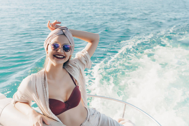 uma linda menina sorridente em óculos de sol goza de viagem marítima, velas no mar
 - Foto, Imagem