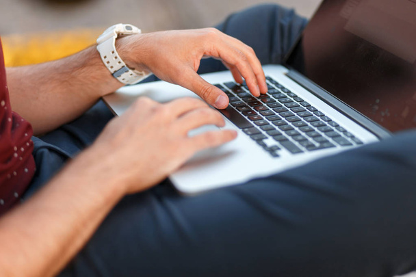 Freelancer man typing text on a laptop on the street. Close-up - Fotografie, Obrázek