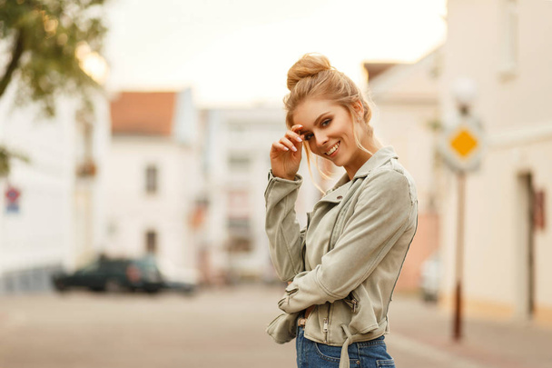 Ευτυχισμένος νεαρής γυναίκας χαμογελαστά σε ένα μοντέρνο σακάκι στην πόλη - Φωτογραφία, εικόνα