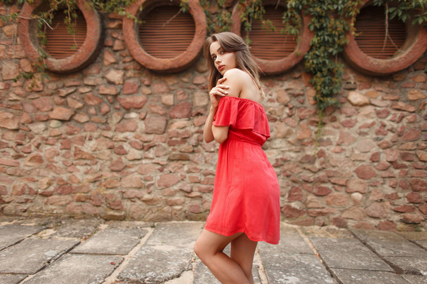 Modne piękny model młoda kobieta w czerwonej sukience w pobliżu kamiennym murem - Zdjęcie, obraz