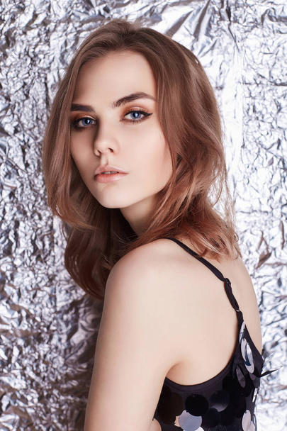 beautiful young woman over shining foil background.studio fashion girl beauty portrait - Фото, изображение
