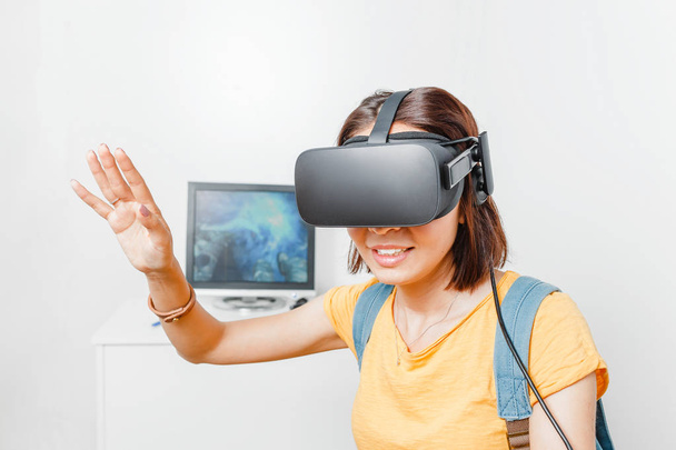 Γυναίκα παίζει βίντεο παιχνίδι με εικονικής πραγματικότητας Vr ακουστικά ενάντια σε οθόνη υπολογιστή - Φωτογραφία, εικόνα