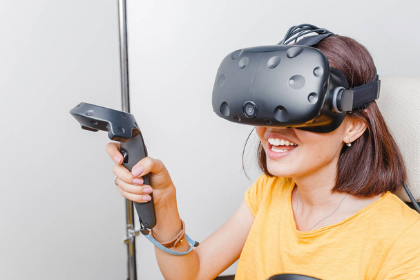 Счастливая женщина с гарнитурой виртуальной реальности и джойстиком, играющая в игры
 - Фото, изображение