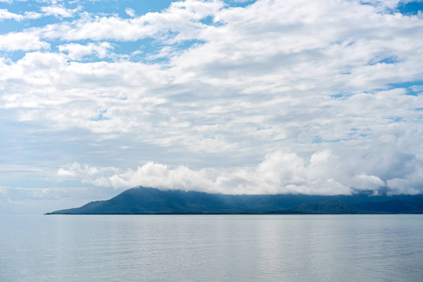 eine friedliche Meereslandschaft mit einer Bergkette am Horizont und einem wolkenverhangenen blauen Himmel - Foto, Bild