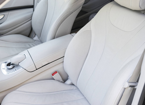 White leather interior of the luxury modern car. Leather comfortable white seats and multimedia. Steering wheel and dashboard. automatic gear stick. Car interior details - 写真・画像