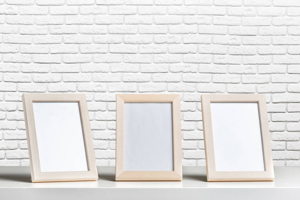 blank white picture frame on the wall and the table wood - Foto, Imagem