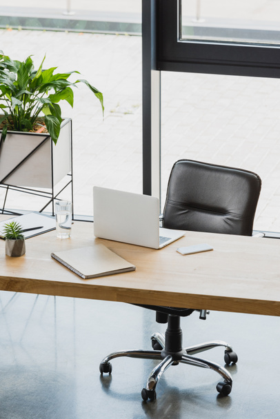 Laptop und Smartphone auf Holztisch im modernen Büro - Foto, Bild