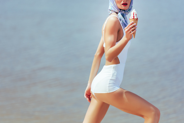cropped view of girl in vintage white swimwear holding waffle cone with ice cream - Fotoğraf, Görsel
