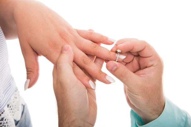 Zbliżenie na człowieka, wprowadzenie pierścionek zaręczynowy na palec jego dziewczyna na białym tle - Zdjęcie, obraz