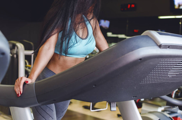 Cropped image of young attractive female working out on treadmill in gym. - Photo, image