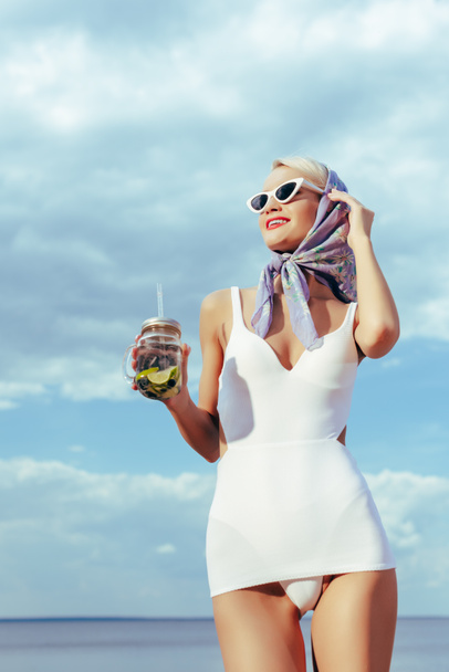 attractive girl in white vintage swimsuit holding mason jar with cocktail - Photo, Image