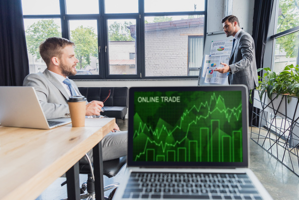 online ticaret grafikler ile laptop ekran ve işadamları proje arkasında tartışırken görmek - Fotoğraf, Görsel