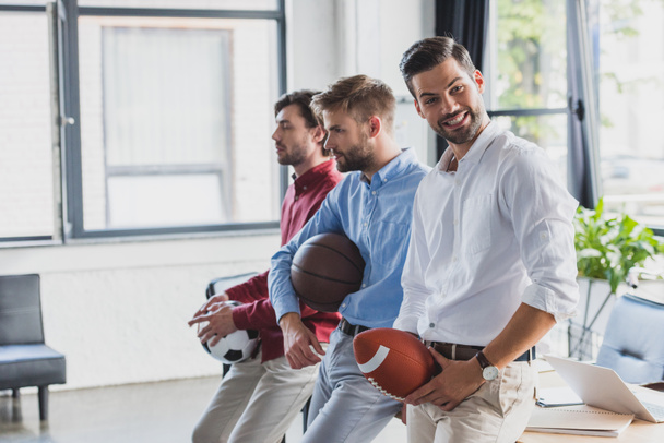 felici giovani uomini d'affari che tengono le palle e distogliendo lo sguardo in ufficio
 - Foto, immagini