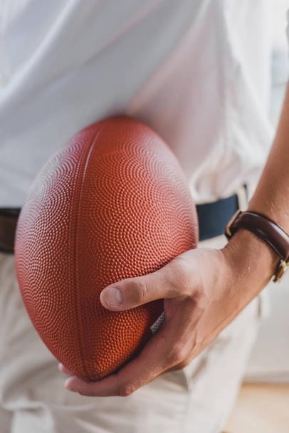 close-up partial view of businessman holding rugby ball in office - Фото, зображення
