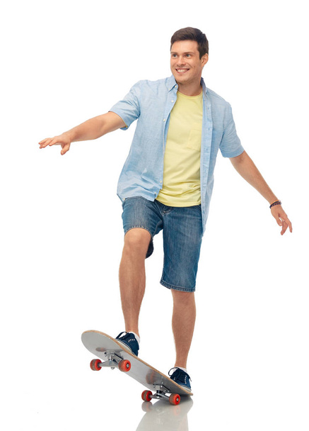 smiling young man riding skateboard over white - Foto, Imagen