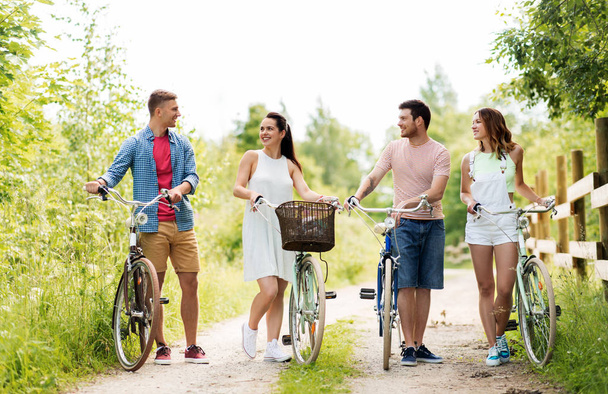 Glückliche Freunde mit Fahrrädern mit festem Gang im Sommer - Foto, Bild