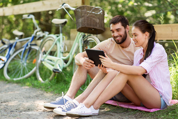 couple with tablet pc and bicycles at summer park - Фото, зображення