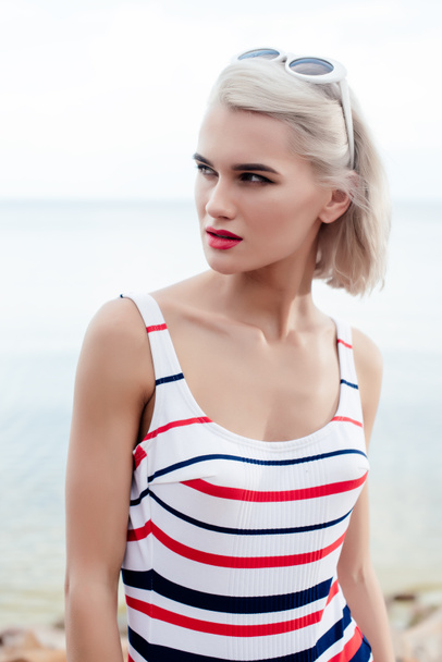 attractive blonde woman posing in retro striped swimsuit and sunglasses - Photo, Image