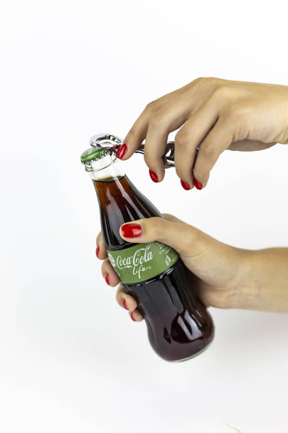 Atlanta, Georgia, USA - July 22, 2018: woman hand with red nails holding Coca-Cola Life Green glass coca-cola contour classic bottle from UK on white background - Fotoğraf, Görsel