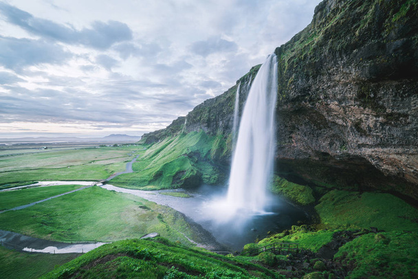 Seljalandsfoss waterfall. Summer landscape with cascade and a river. Famous tourist attraction of Iceland - Photo, Image