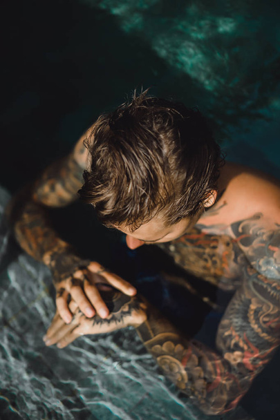 jeune homme beau tatouages reposant dans la piscine extérieure. Un homme tatoué dans la piscine s'amuse. sur bali, indonésie
 - Photo, image