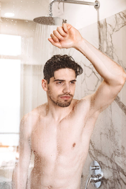 Charming young naked man having a shower - Foto, Imagen