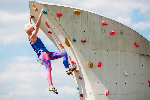 Photo from side of sports woman climbing on rocky summer day - 写真・画像