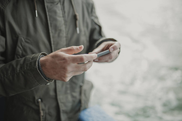 Close up of man hands holding a mobile phone while travel in a boat. - Foto, immagini