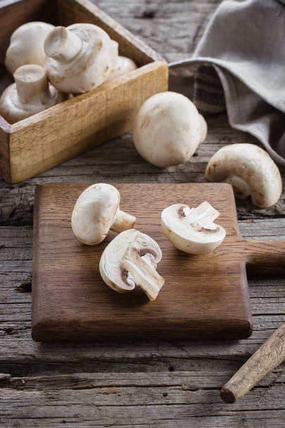 Fresh Raw Mushrooms Champignons on a Wooden Cutting Board on Old Rustic Wooden Table Background - Фото, изображение