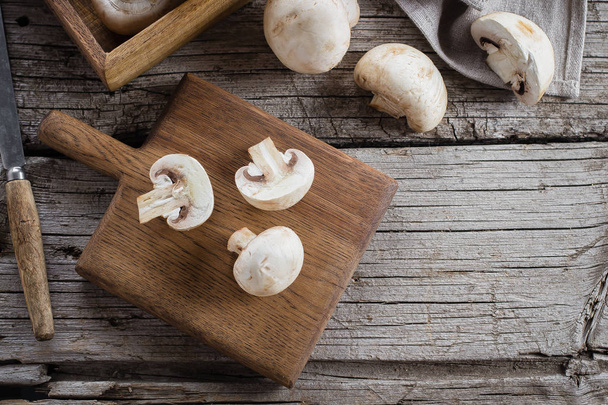Fresh Raw Mushrooms Champignons on a Wooden Cutting Board on Old Rustic Wooden Table Background. Top view, copy space - Photo, Image