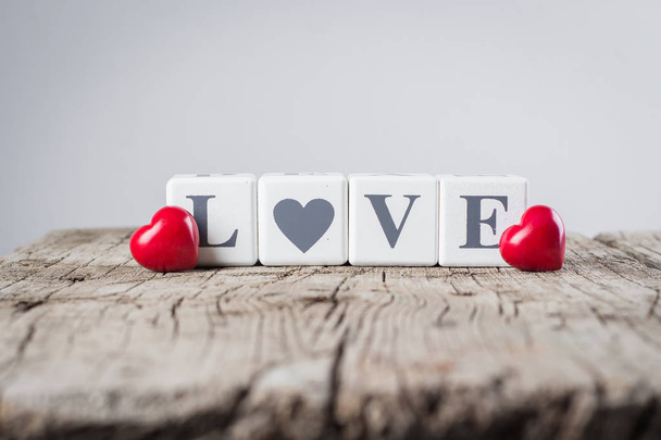 Concepto de tarjeta de San Valentín. Idea creativa. Mensaje de amor escrito en bloques de madera y corazón rojo cerámico sobre fondo de madera viejo
. - Foto, imagen