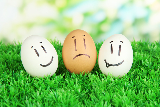 Eggs with funny faces on grass on bright background - Фото, зображення