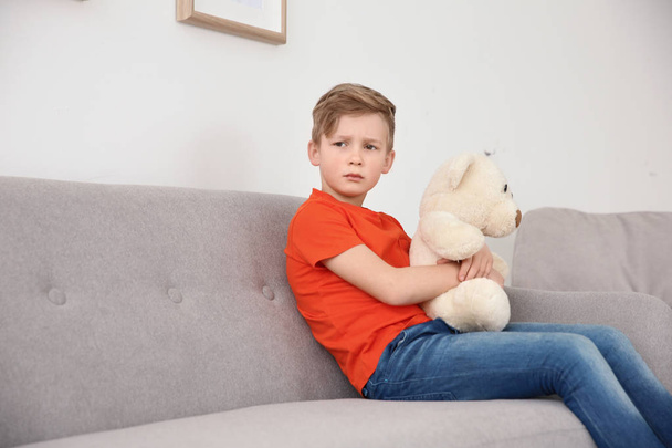 Little autistic boy sitting on sofa with toy at home - Фото, зображення