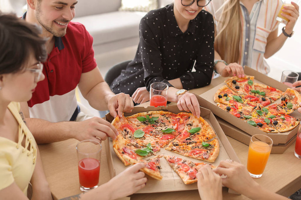 Young people eating delicious pizzas at table, closeup - Foto, Imagen