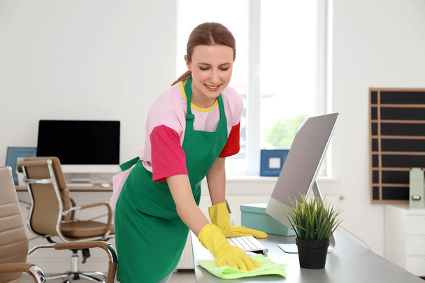 Mujer joven en delantal y guantes de oficina de limpieza
 - Foto, imagen