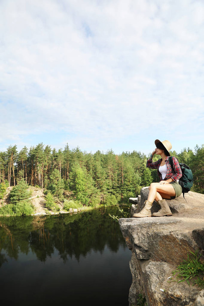 Young woman on rock near lake and forest. Camping season - Valokuva, kuva