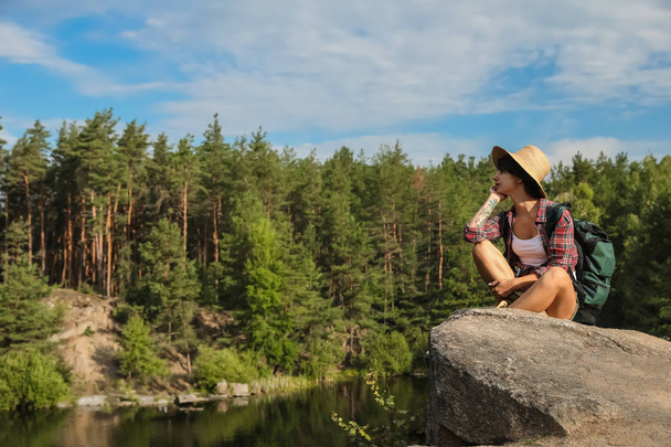 Young woman on rock near lake and forest. Camping season - Photo, Image
