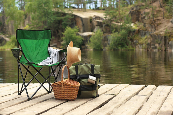 Set of camping equipment on wooden pier near lake - Foto, Imagen