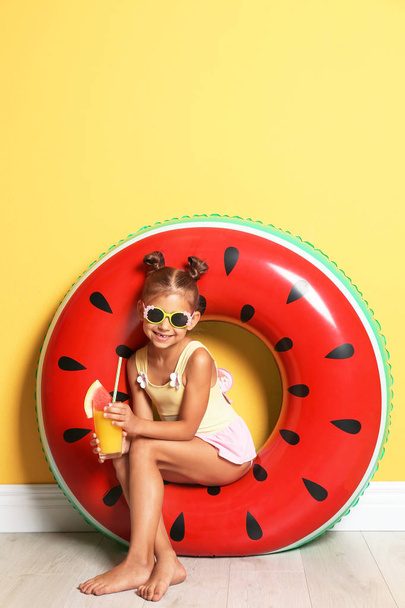 Cute little girl with inflatable ring and glass of cocktail near color wall - Fotografie, Obrázek