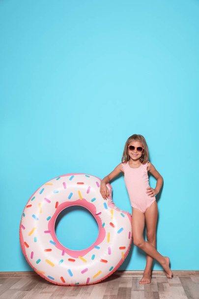 Schattig klein meisje met heldere opblaasbare ring in de buurt van kleur muur - Foto, afbeelding